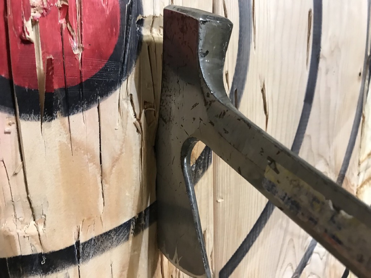 Close-up of an axe head buried in a target board
