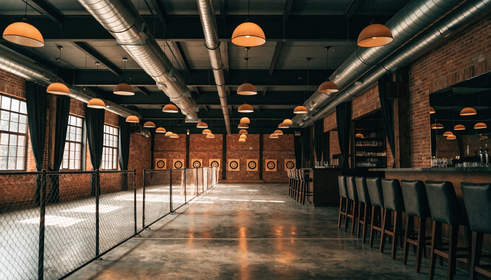 Axe throwing venue with targets on a brick wall and a bar alongside