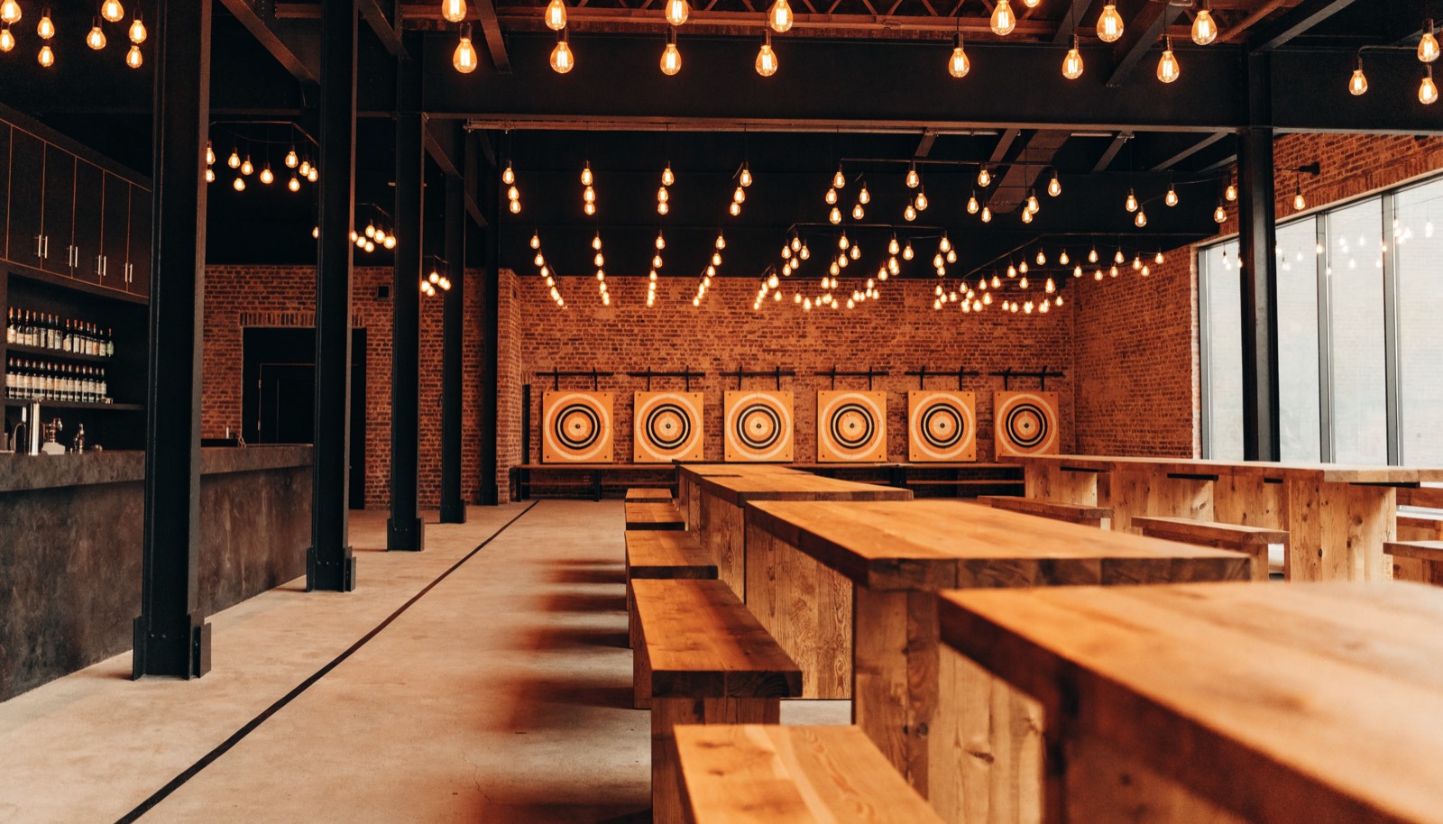 Communal tables and benches facing a wall of axe throwing targets